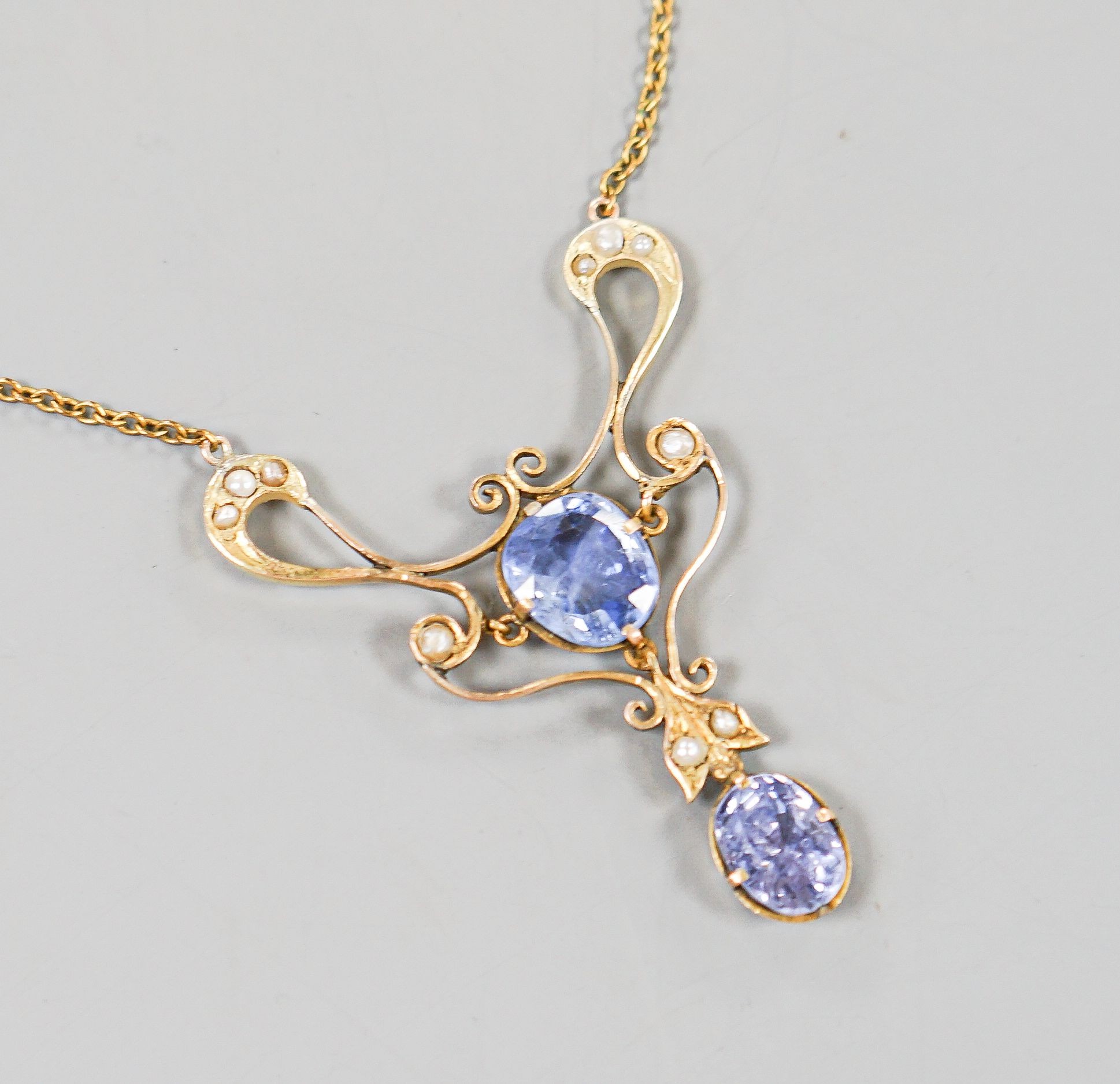 An early 20th century 9ct, two stone Ceylon sapphire and multi seed pearl set pendant necklace, pendant 49mm, chain approx. 40cm, gross weight 9.2 grams